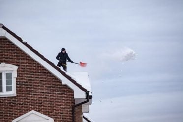 Man shoveling snow from a Huntsville home roof by KSC